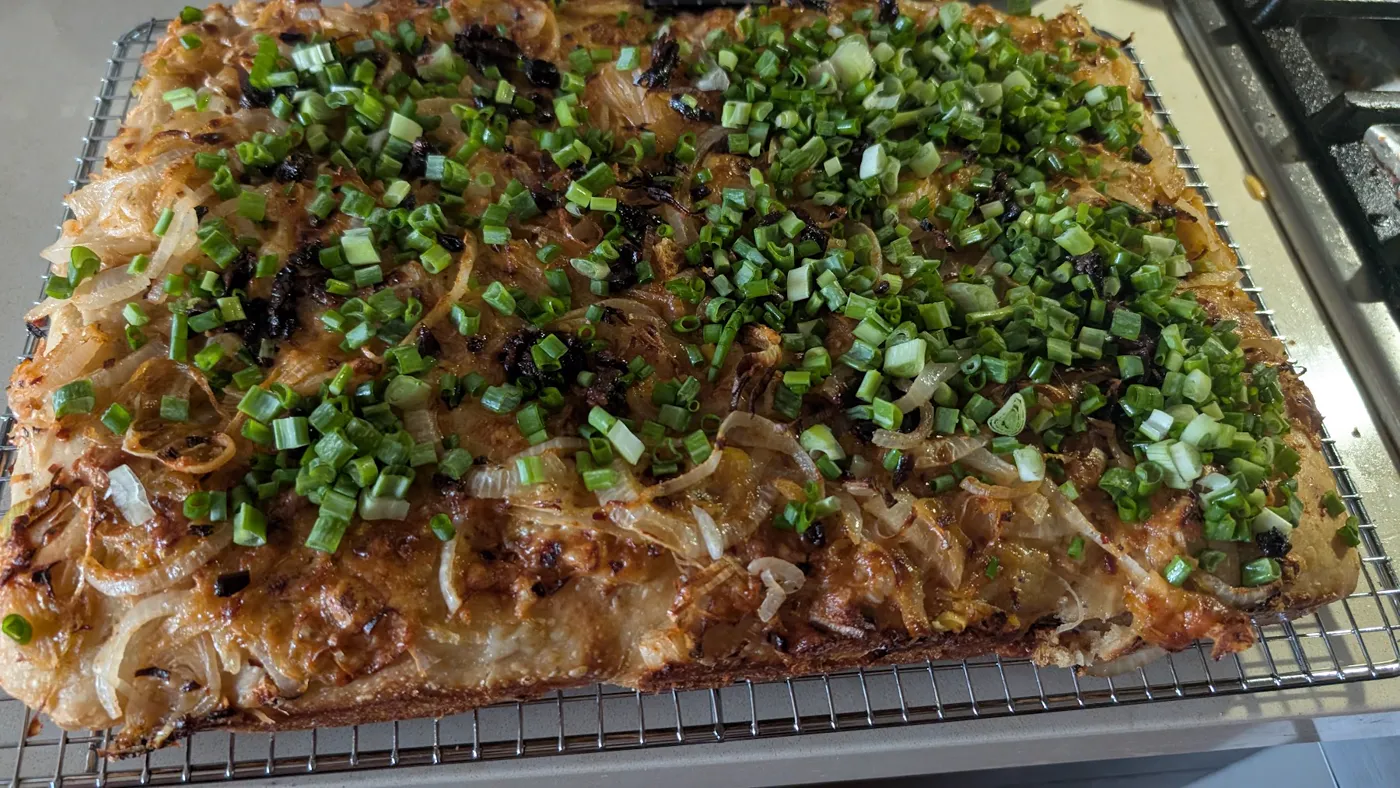 Baked focaccia with caramelized onions and green negi, cooling on a rack