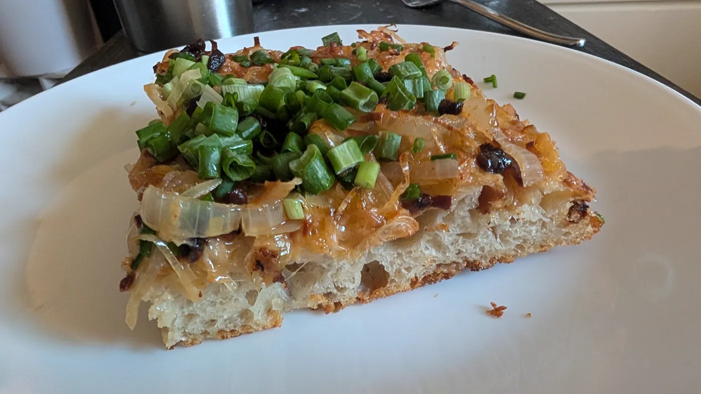 A slice showing the open, airy crumb under caramelized onions